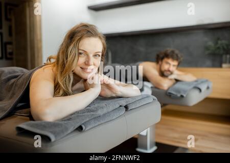 Beau couple allongé dans un salon de spa et attendant le masseur pour le massage profond du dos et la détente. Le bien-être et les loisirs pour les soins de santé ensemble. Concentrez-vous sur la femme souriante. Banque D'Images