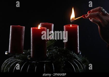 Couronne ou couronne de l'Avent. Femme lignant des bougies rouges. Composition de Noël. France. Banque D'Images