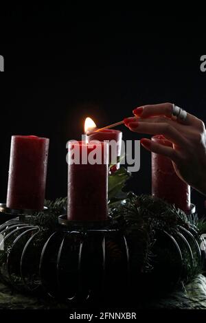 Couronne ou couronne de l'Avent. Femme lignant des bougies rouges. Composition de Noël. France. Banque D'Images