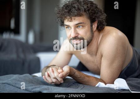 Bel homme allongé dans un salon de spa, qui attend un massage du dos et une relaxation. Le bien-être et les loisirs pour les soins de santé ensemble. Concentrez-vous sur l'homme. Regardez la caméra. Banque D'Images