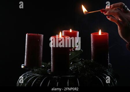 Couronne ou couronne de l'Avent. Femme lignant des bougies rouges. Composition de Noël. France. Banque D'Images