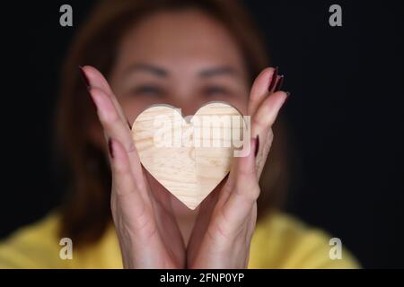 Femme tenant un coeur en bois. Symbole d'amour. France. Banque D'Images