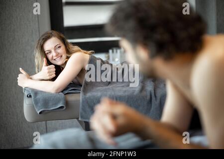 Beau couple allongé dans un salon de spa et attendant le masseur pour le massage profond du dos et la détente. Le bien-être et les loisirs pour les soins de santé ensemble. Concentrez-vous sur la femme montrant le signe ok. Banque D'Images