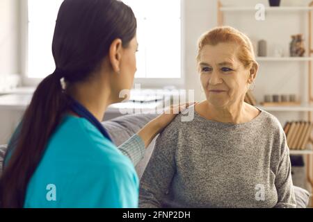 Gros plan d'une femme âgée qui reçoit le soutien d'une jeune infirmière ou d'un médecin. Banque D'Images