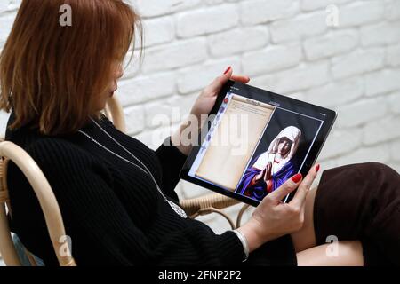 Femme priant le Rosaire sur une tablette numérique iPad. France. Banque D'Images