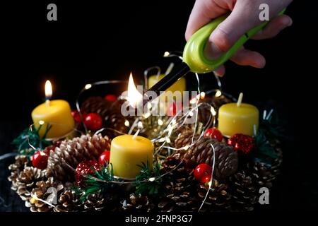 Couronne ou couronne de l'Avent. Femme lignant des bougies jaunes. Composition de Noël. France. Banque D'Images