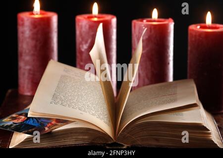 Bible ouverte avec quatre bougies rouges de l'Avent. France. Banque D'Images