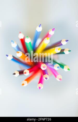 Les crayons de couleur sont en éventail dans un verre sur fond blanc Banque D'Images