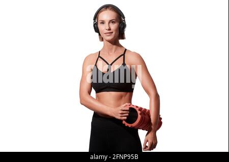 Femme sportive forte avec rouleau de massage et casque sur blanc arrière-plan isolé Banque D'Images