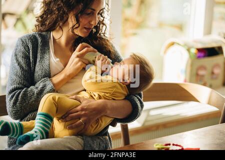 nouveau-né buvant du lait au biberon. Mignon tout-petit dans les bras de la mère avec bouteille de lait. Banque D'Images