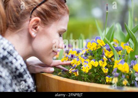 Jeune femme sentant des fleurs jaunes dans le parc pendant le portrait du printemps Banque D'Images