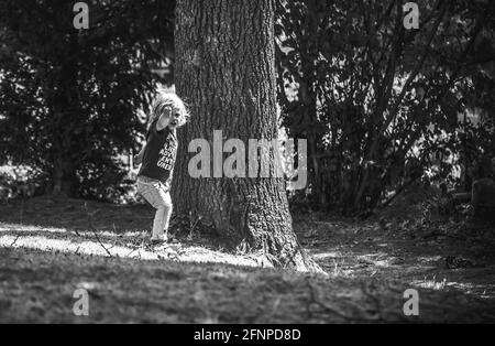 Jeune garçon aux cheveux blonds jouant dans un parc ombragé en été Banque D'Images