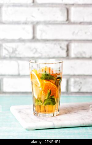 Le verre de thé glacé aux agrumes sur un plateau en marbre et une table en bois. Cuba libre ou long Island cocktail, boisson froide, ou limonade avec fruits et menthe. Copier Banque D'Images