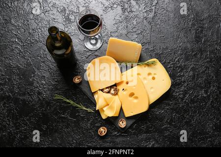 Savoureux fromage, noix et vin sur fond sombre Banque D'Images