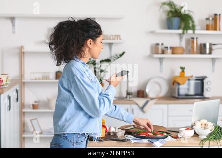 Jeune femme prenant la photo de pizza savoureuse dans la cuisine Banque D'Images