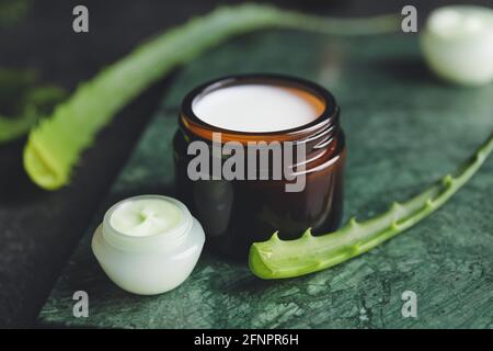 Pots à la crème naturelle et feuilles d'aloès sur fond de marbre Banque D'Images