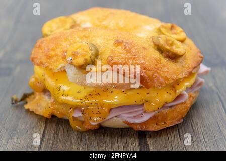 Le fromage fondu s'égoutte sur les piles de jambon tranché servi à l'intérieur d'un bagel de petit déjeuner jalepeno coupé en deux. Banque D'Images