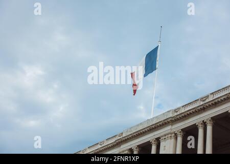 Drapeau de France agitant dans le vent sur le dessus de bâtiment administratif contre le ciel sombre pluvieux. Concept de voyage en France. Image de haute qualité Banque D'Images