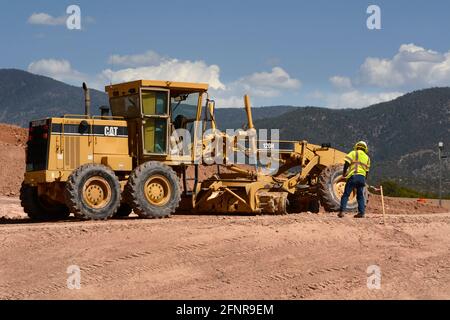 Un conducteur d'équipement lourd utilise une niveleuse Caterpillar 120H pour déplacer la terre sur un chantier de construction de routes à Santa Fe, Nouveau-Mexique. Banque D'Images