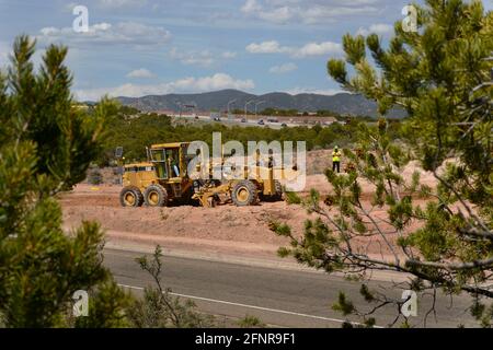 Un conducteur d'équipement lourd utilise une niveleuse Caterpillar 120H pour déplacer la terre sur un chantier de construction de routes à Santa Fe, Nouveau-Mexique. Banque D'Images