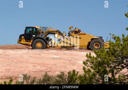 Un conducteur d'équipement lourd utilise une décapeuse automotrice 623H Caterpillar pour éliminer la saleté sur le chantier d'amélioration sur autoroute de Santa Fe, Nouveau-Mexique. Banque D'Images