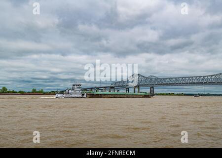 Bateau à remorqueurs poussant la barge sur le fleuve Mississippi boueux. Pont de la ville de Crescent en arrière-plan Banque D'Images