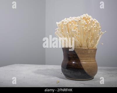 Champignons enoki dans un bol en argile sur la table Banque D'Images