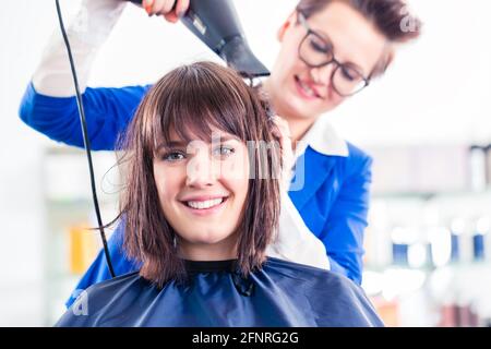 Coiffeur femme sécher les cheveux des femmes avec séchoir à shop Banque D'Images