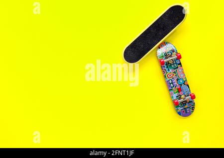 Deux mini-jouets de skateboard avec roues rouges sur fond jaune. Concept de loisirs pour adolescents. Pose à plat. Vue de dessus. Copier l'espace Banque D'Images
