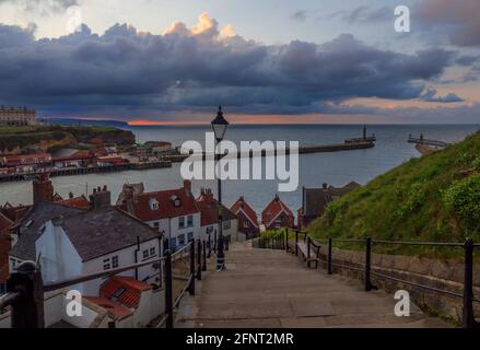 La vue depuis les célèbres 199 marches de Whitby. Pris comme le soleil se couche créant une traînée de rose vif à l'horizon, en regardant au-dessus du port. Banque D'Images