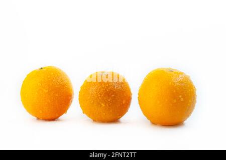 Gros plan de trois oranges recouvertes de gouttelettes d'eau isolées sur fond blanc Banque D'Images