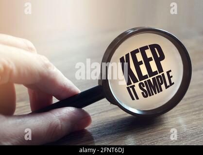 Main tenant la loupe avec le mot maintenez-la simple. Concept de l'éducation et des affaires Banque D'Images
