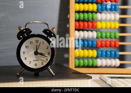 Réveil noir, abacus coloré et calculatrice blanche sur fond gris - rentrée scolaire Banque D'Images