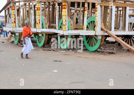 La photo montre un vieil homme qui marche devant le ratha inachevé. La composition de l'image est perfectionnée par la combinaison de l'homme et de rath. Banque D'Images