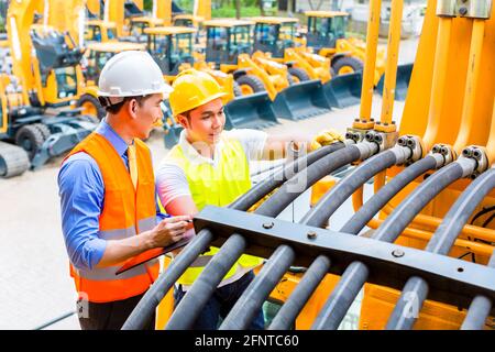 Mécanicien moteur asiatique discuter avec liste des tâches de l'ingénieur dans la construction de l'atelier de la machine Banque D'Images