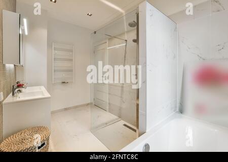 Décoration intérieure moderne, salle de bain lumineuse avec baignoire blanche et mobilier et cabine de douche en verre, décoration élégante et minimaliste Banque D'Images