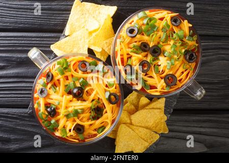 La trempette à sept couches est un hors-d'œuvre américain à base d'ingrédients typiques de la cuisine Tex-Mex, en gros plan dans le verre sur la table. Vue horizontale du dessus à partir de Banque D'Images