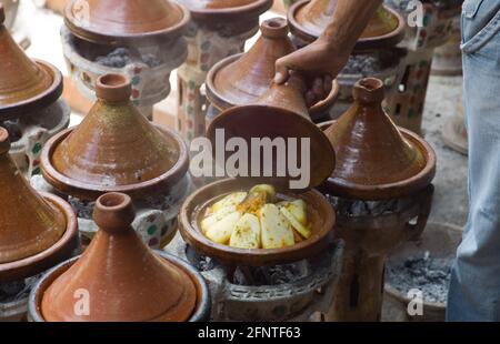 Main d'homme cuisant le Tajine traditionnel à la vapeur un barbecue extérieur sur la place de la ville dans la rue Morroco Banque D'Images