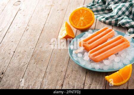 Pop-sicles orange sur une table en bois Banque D'Images