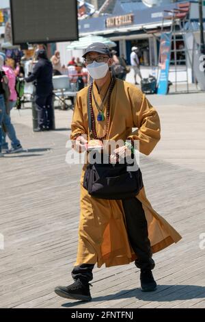 Un homme qui prétend être bouddhiste offre des livres et des bracelets et demande des dons. Sur la promenade de Coney Island, Brooklyn, New York. Banque D'Images