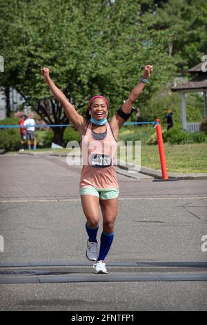 Une jeune femme est jubilante à l'approche de la ligne d'arrivée du semi-marathon du NYCRuns Queens à Flushing Meadows Corona Park à New York. Banque D'Images