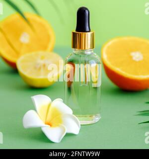 Sérum cosmétique vitamine C en flacon de verre avec pipette compte-gouttes agrumes et fleur de plumeria. Huile essentielle d'orange ingrédients d'agrumes couleur vitamine C. Banque D'Images