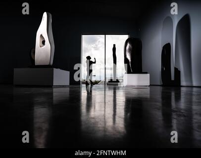 Une femme est silhouetée contre une fenêtre alors qu'elle photographie l'exposition Barbara Hepworth: Art et vie au musée d'art Hepworth Wakefield à Wakefield, West Yorkshire pour marquer leur 10e anniversaire. Date de la photo: Mercredi 19 mai 2021. Banque D'Images