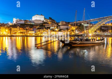 Blick über die traditionellen Rabelo Boote am Douro Ufer in Betrieb einer Bürgen und Verkauf von Dienstleistungen Die Brücke Ponte Dom Luís I in der Abend Banque D'Images