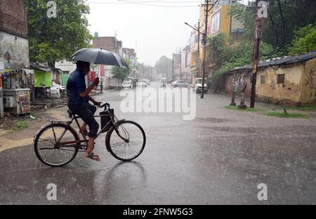 Prayagraj, Uttar Pradesh, Inde. 19 mai 2021. Prayagraj: Un cycliste utilise un parapluie pour être à l'abri de la pluie douche à Prayagraj le mercredi 19 mai 2021. Credit: Prabhat Kumar Verma/ZUMA Wire/Alamy Live News Banque D'Images