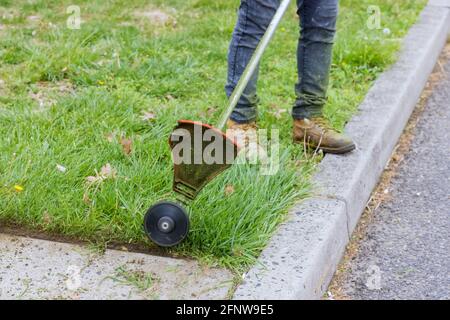 Gros plan, homme main à l'aide d'une tondeuse à gazon pour couper de l'herbe mise au point sélective verte à portée de main Banque D'Images