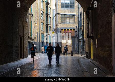 Personnes marchant dans Clink Street, une petite rue pavée dans le quartier de Bankside, London Borough of Southwark, Angleterre, Royaume-Uni Banque D'Images