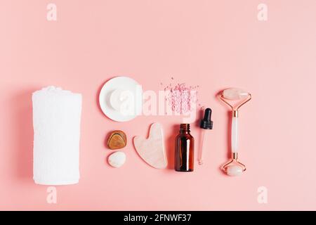 Composition spa sur fond rose pastel. Cosmétiques naturels bio bouteille d'huile, crème, argile, sel, outil de massage gua sha accessoires plan Banque D'Images
