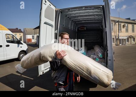 Employé debout près d'un camion rempli de tapis. Concept de service de nettoyage Banque D'Images