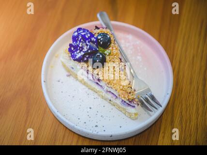 Gâteau au fromage aux baies bleues dans un plat blanc sur une table en bois. Banque D'Images